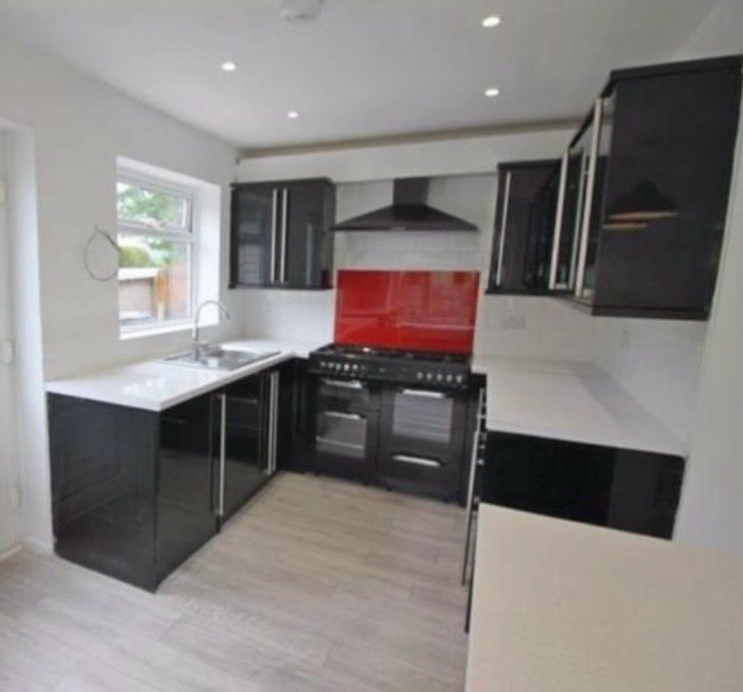 Kitchen before: dated black-gloss units and red splashback