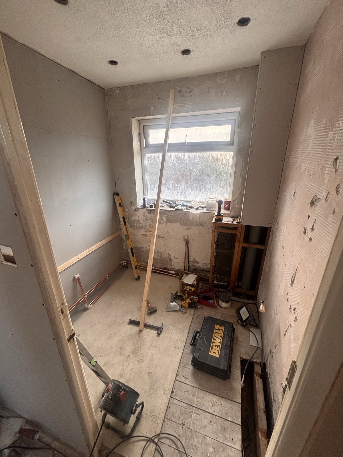 Bathroom before: room stripped to bare plasterboard and copper first fix