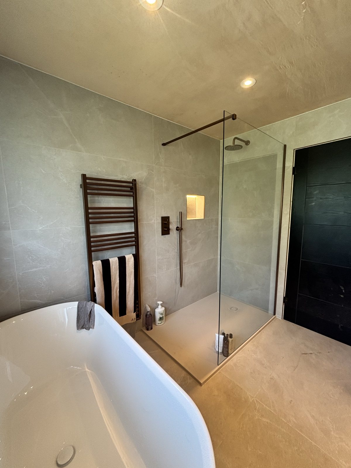 Finished ensuite with freestanding bath and stone tiles, after