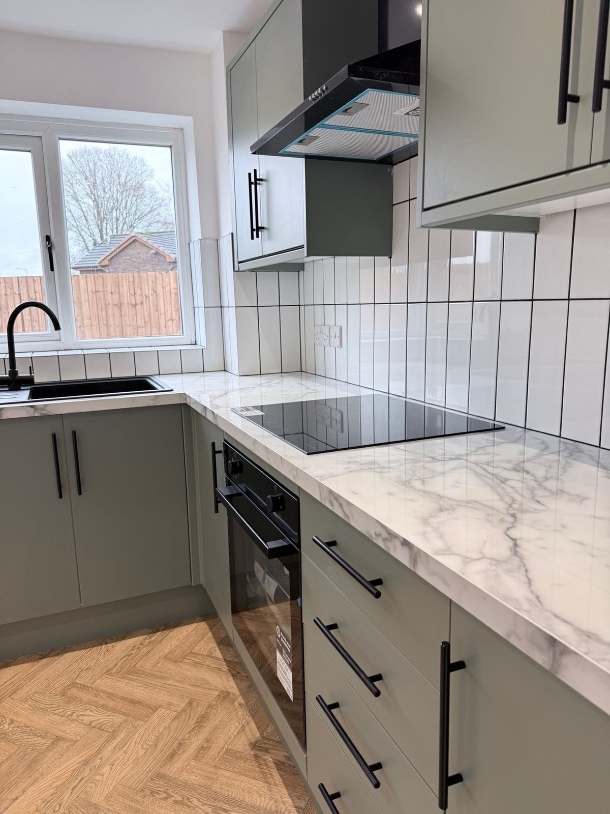 After: cooking area with vertical subway tiles and black appliances