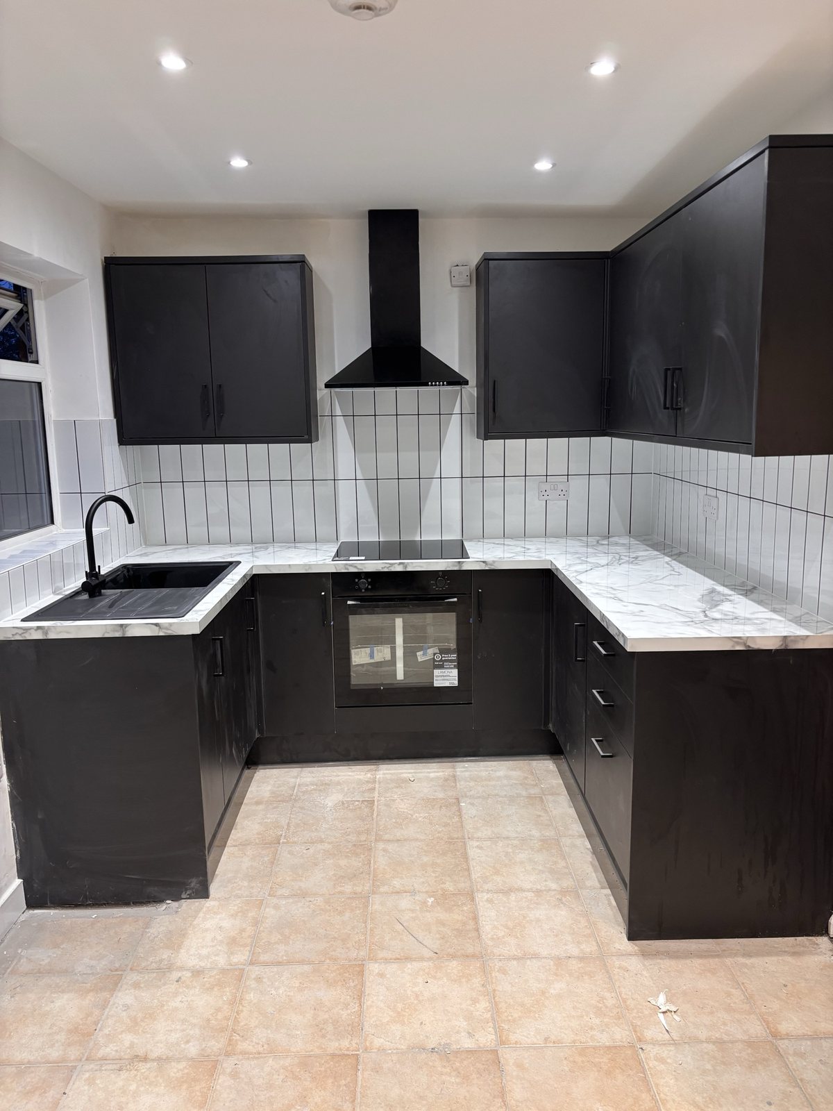Finished matte black kitchen with marble worktop and finger tiles, after