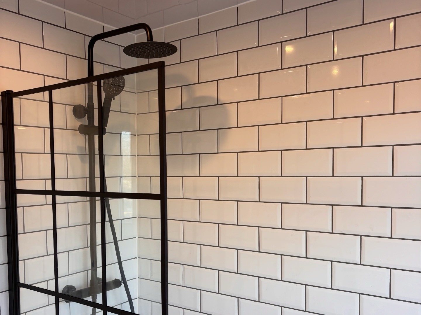 After: matte black rain shower over the bath